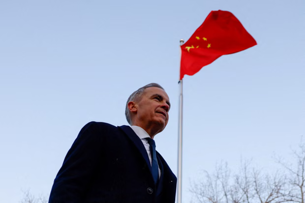 Mark Carney caminhando com uma bandeira chinesa hasteada acima da cabeça.