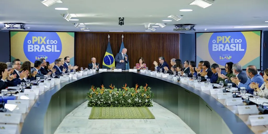 Presidente Lula discursa em reunião ministerial no Palácio do Planalto, com ministros aplaudindo. (Foto: operamundi.uol.com.b